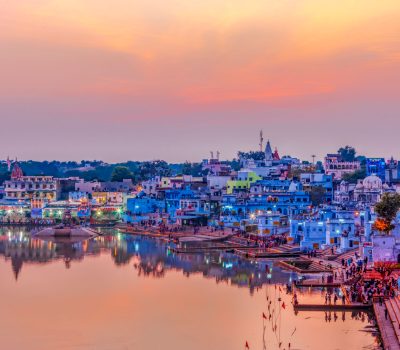 Pushkar Holy Lake at sunset. Hindu pilgrims bathing in sacred Lake Pushkar (Sarovar) on ghats. Countless people in colourful attire gather to take a dip in the Holy Lake and pray to deities.